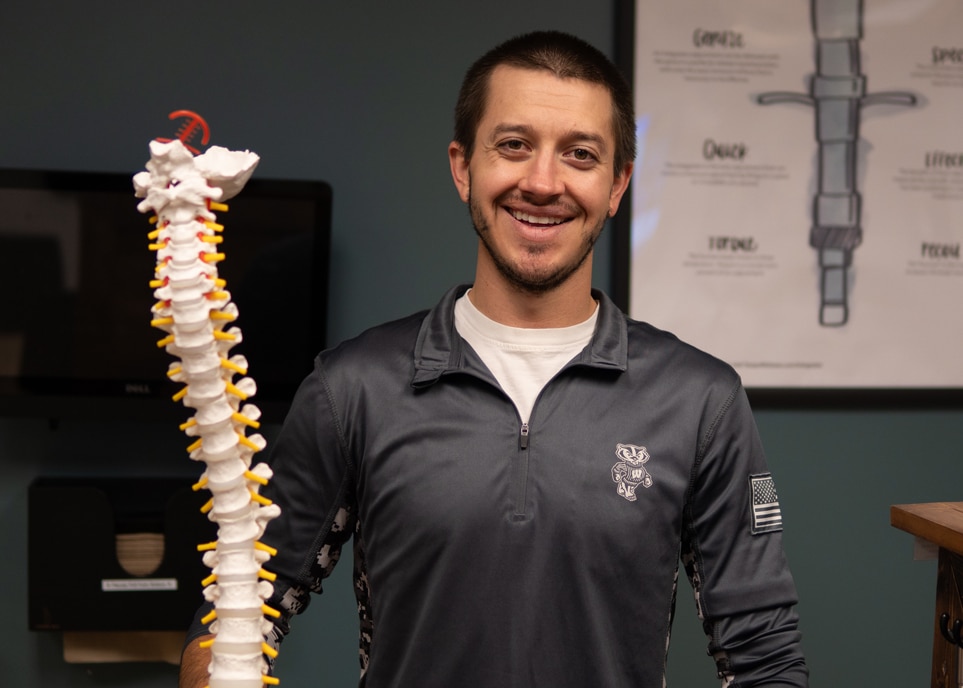 Owner of advantage chiropractic holding up a image of a spine.