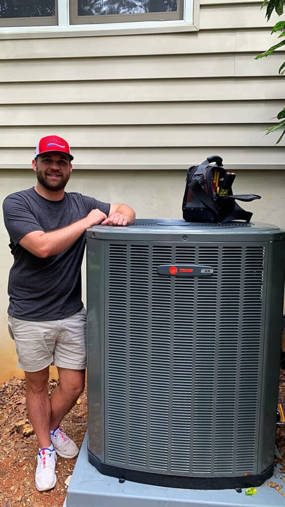 Hvac owner standing next to ac unit happy with his hvac marketing results.