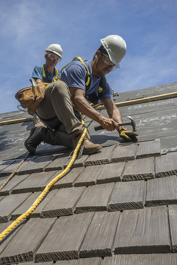Roofing contractor nailing in shingles